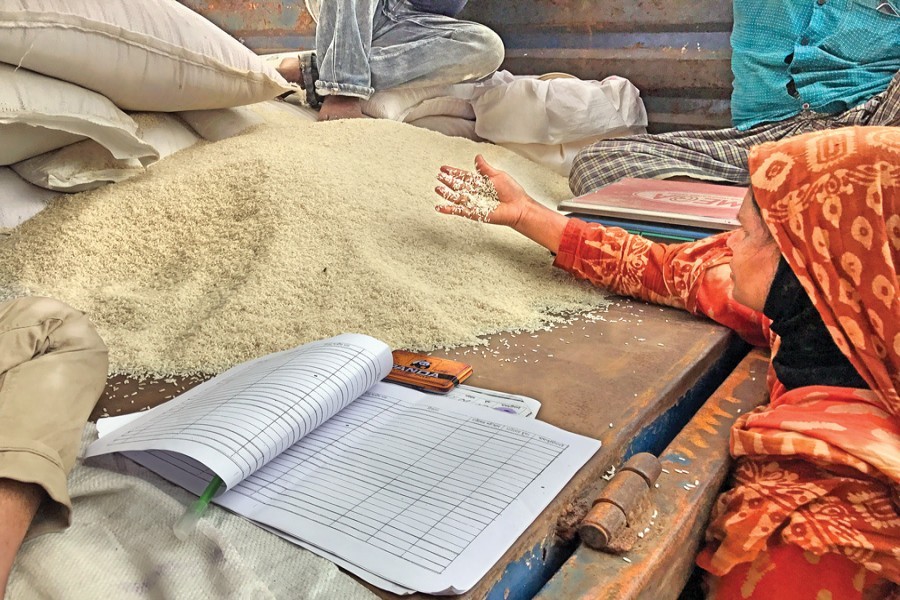 A consumer checks the quality of rice put on sale at Jurain in Old Dhaka as the open-market sale (OMS) began across the country on Sunday.— FE Photo by Shafiqul Alam