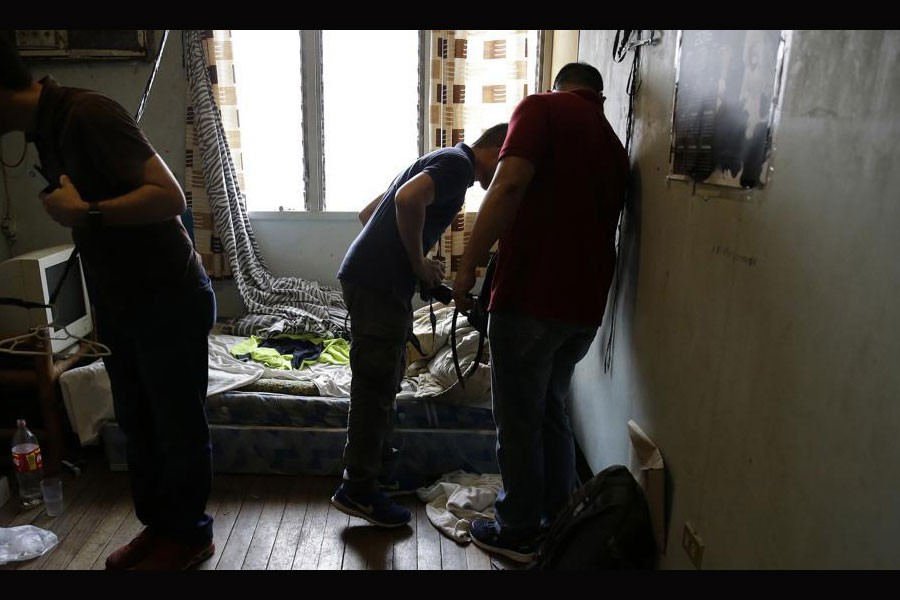 In this April 20, 2017, photo, investigators check a room in the home of suspected child webcam cybersex operator, David Timothy Deakin, from Peoria, Ill., during a raid in Mabalacat, Philippines.(AP Photo)