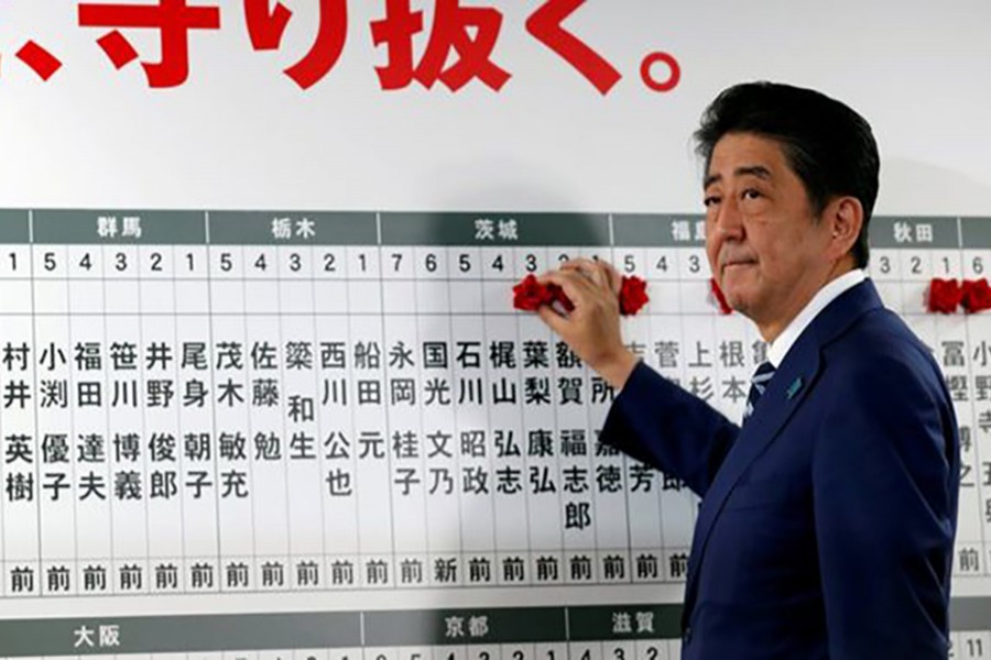 Japan's Prime Minister Shinzo Abe, leader of the Liberal Democratic Party (LDP), puts a rosette next to his name after the lower house election on Sunday. - Reuters
