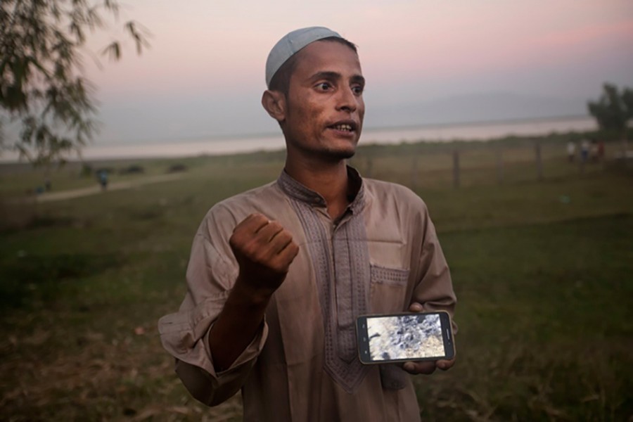 Osman Gani, a Rohingya man from Myanmar, shows a video clip that he shot on his mobile phone as he describes the violence standing on the bank of the Naf River. - AP file photo