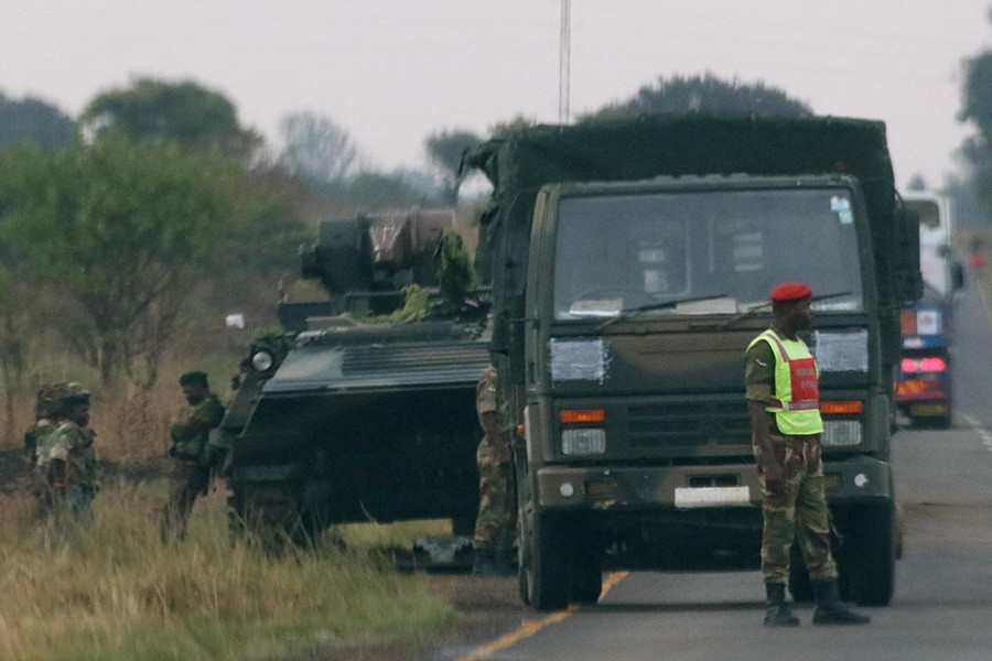 Soldiers stand beside military vehicles just outside Harare, Zimbabwe on Tuesday. - Reuters photo