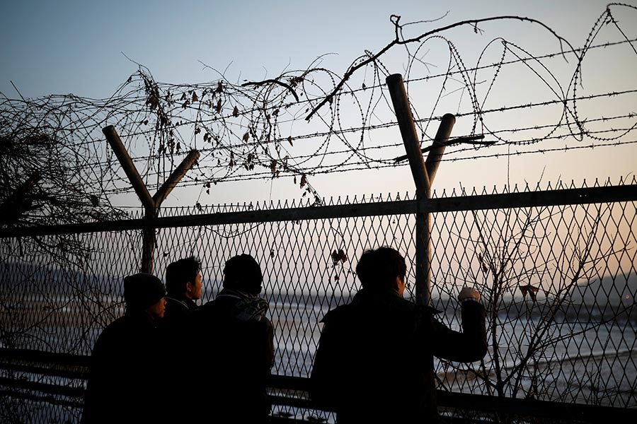 People look toward the north through a barbed-wire fence near the militarised zone separating the two Koreas, in Paju, South Korea on Thursday. - Reuters