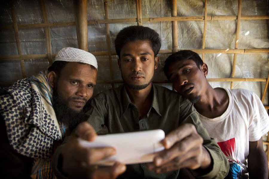 In this Jan. 14, 2018 photo, Rohingya Muslim refugee Mohammad Karim, 26, center, shows a mobile video of Gu Dar Pyin’s massacre to other refugees in Kutupalong refugee camp, Bangladesh. On Sept. 9, a villager from Gu Dar Pyin, captured three videos of mass graves,photo: AP
