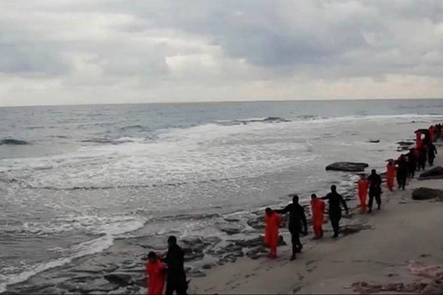 This image made from a video released on February 15, 2015, by militants in Libya claiming loyalty to the Islamic State group purportedly shows Egyptian Coptic Christians in orange jumpsuits being led along a beach, each accompanied by a masked militant before the men are simultaneously beheaded - AP file photo