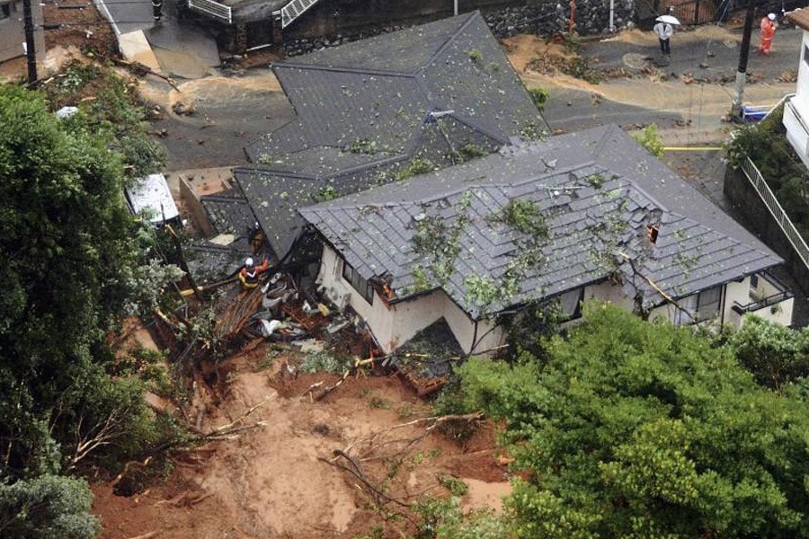 Rescue workers are seen next to houses damaged by a landslide following heavy rain in Hiroshima, western Japan, in this photo taken by Kyodo July 7, 2018. Kyodo/via Reuters.