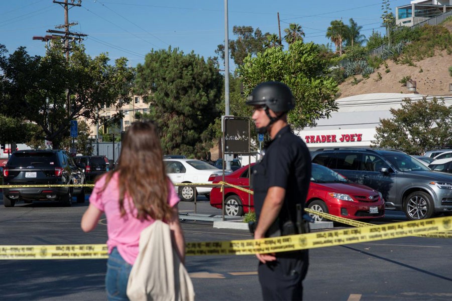A police officer talks with a woman in a parking lot across the street from a Trader Joe's store where a hostage situation unfolded in Los Angeles, California, Saturday July 21, 2018 – Reuters