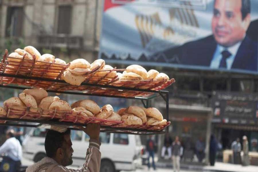 A man carries breads on his head along a busy street near a banner for Egypt's President Abdel Fattah al-Sisi from the campaign titled “Alashan Tabneeha” (So You Can Build It) after election results in Cairo, Egypt, April 3, 2018. Reuters/Files