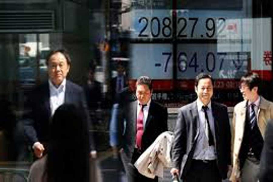 People walk past an electronic board showing Japan's Nikkei average outside a brokerage in Tokyo, Japan, March 23, 2018. Reuters/File Photo