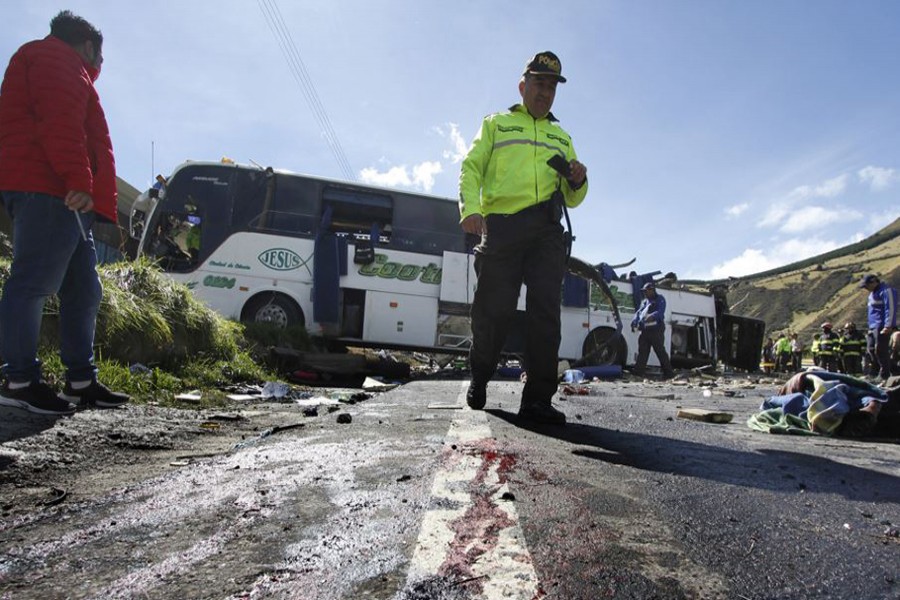 A police officer walks past a Colombian-registered bus that crashed while traveling to Quito, Ecuador on Tuesday — AP photo