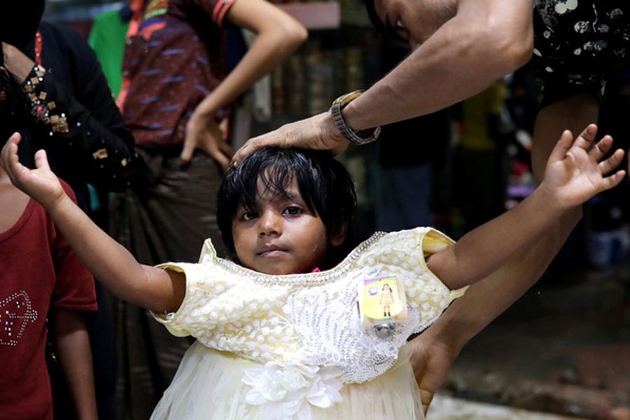A minor Rohingya girl is trying a froc at a Kutupalong shop