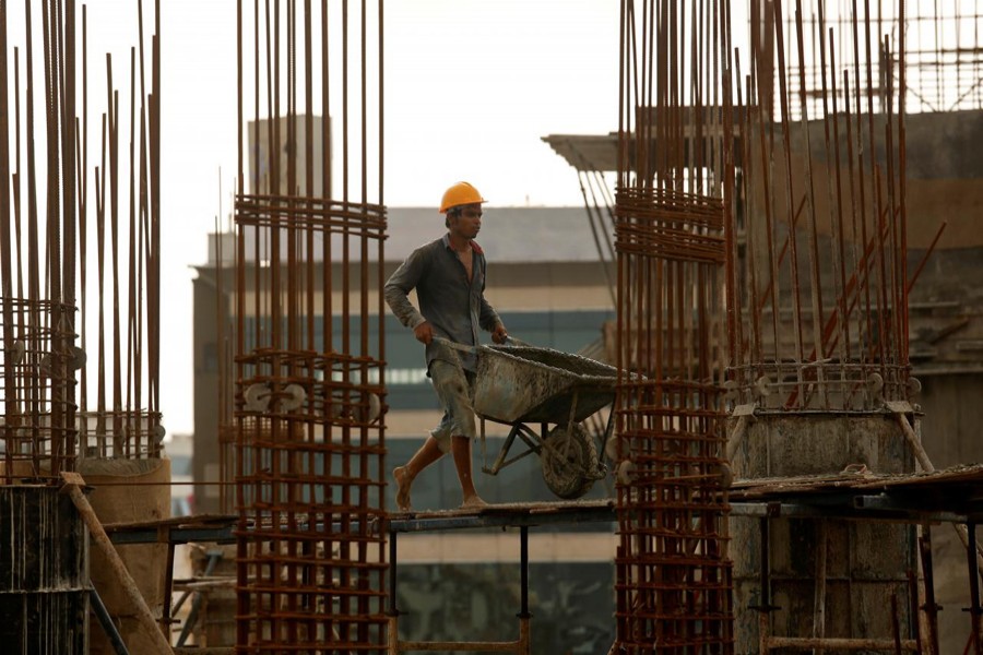 A worker pushes a wheelbarrow to collect cement at a construction site of a residential building in Mumbai, India, August 31, 2018. Reuters
