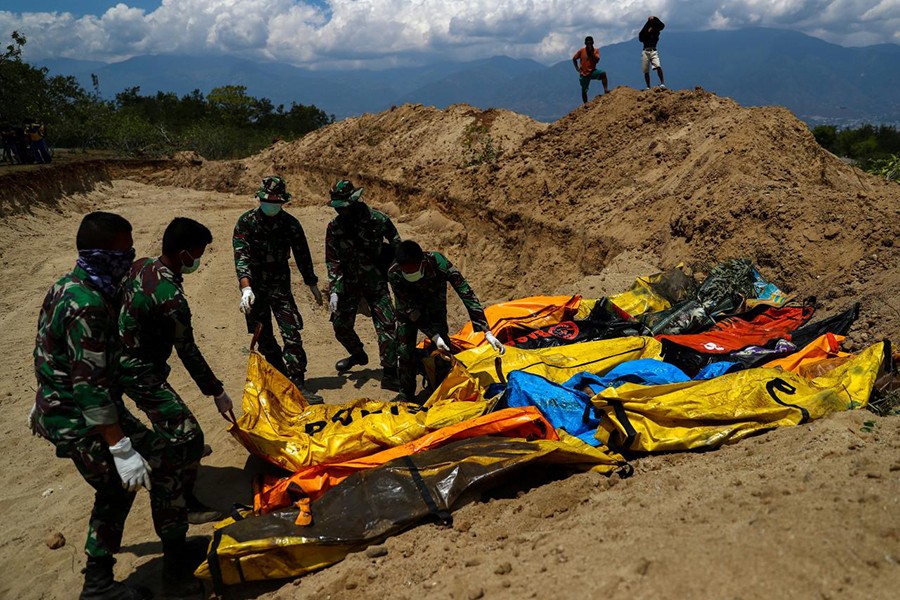 Soldiers move dead bodies of the victims of the earthquake and tsunami during a mass burial at the Poboya Cemetery in Palu, Central Sulawesi, Indonesia on Tuesday — Reuters photo