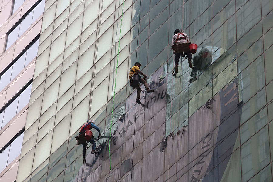 Workers seen painting the outside of a high-rise building in the capital without minimum safety equipment — FE file photo