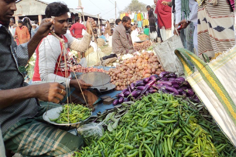 A seller weighing green chilli at Madhupur Bazar in Khetlal upazila of Joypurhat — FE Photo