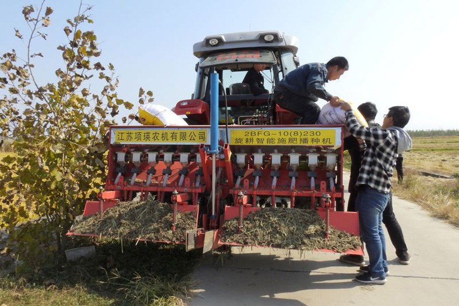 Staff members taking part in the experiment on automated farming machinery load fertilizer onto an automated tractor near a field in Xinghua, Jiangsu province, China, October 30, 2018. Reuters/Files