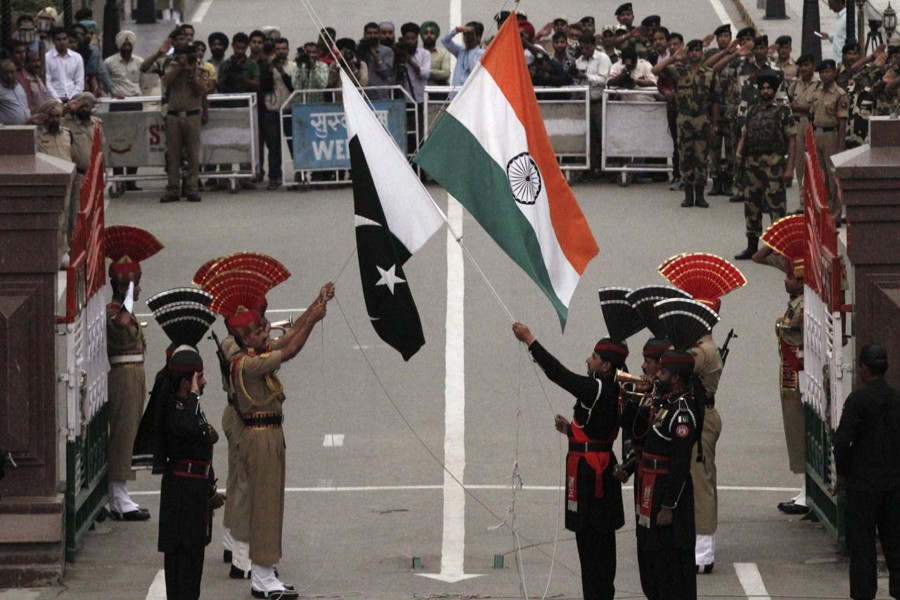 Pakistani rangers (wearing black uniforms) and Indian Border Security Force (BSF) officers lower their national flags during a daily parade at the Pakistan-India joint check-post at Wagah border, near Lahore November 3, 2014. Reuters/File Photo
