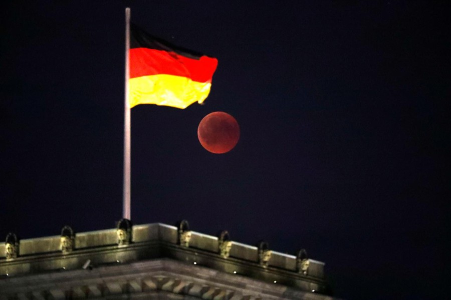 The moon is seen during a lunar eclipse next to the German national flag on top of the Reichstag building in Berlin, Germany, July 27, 2018. Reuters/Files