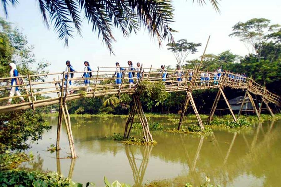Some students crossing the Chitra river by using a bamboo bridge under Bagharpara upazila of Jashore district 	— FE Photo