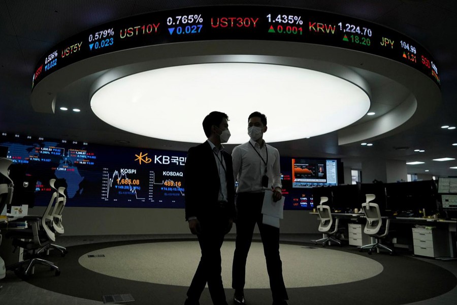 Currency dealers walk past an electronic board showing the Korea Composite Stock Price Index (KOSPI) at a dealing room of a bank in Seoul, South Korea, March 13, 2020 — Reuters