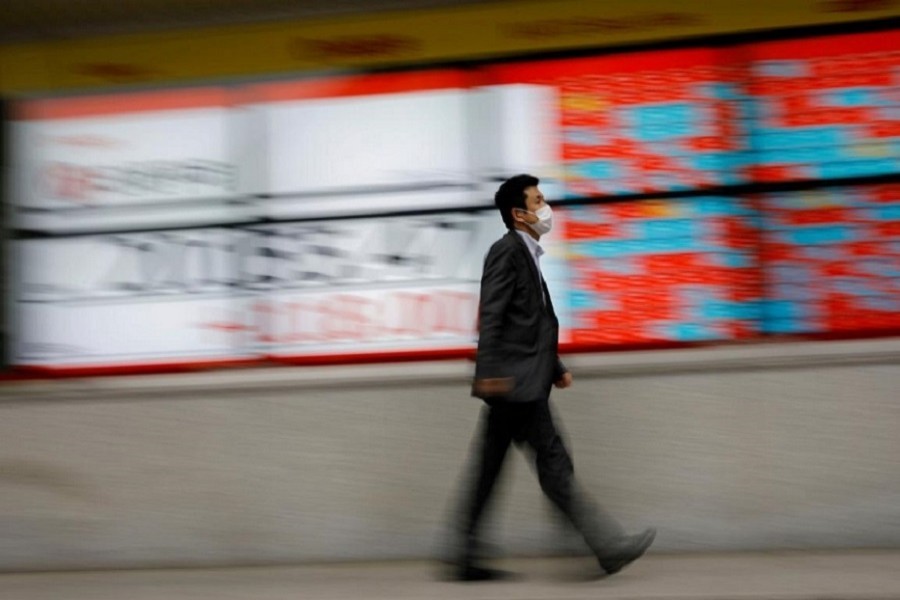 A man wearing a protective face mask, following the coronavirus disease (COVID-19) outbreak, walks in front of a stock quotation board outside a brokerage in Tokyo, Japan, May 18, 2020. — Reuters/Files