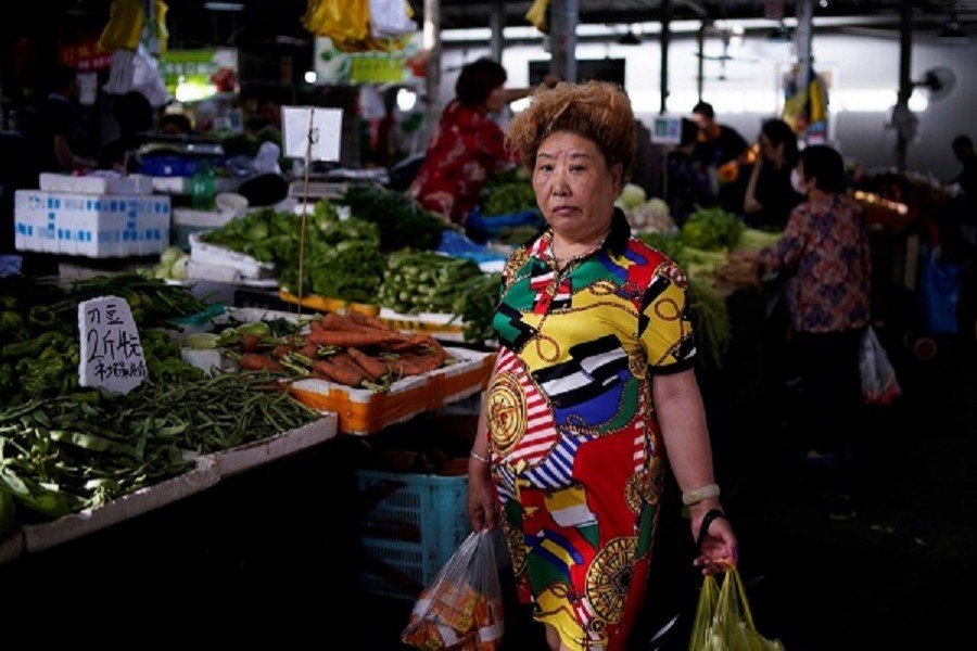 A woman carries vegetables and food at a market, following the coronavirus disease (Covid-19) outbreak, in Shanghai, China. June 09, 2020 — Reuters/Files