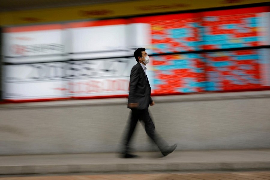 A man wearing a protective face mask, following the coronavirus disease (Covid-19) outbreak, walks in front of a stock quotation board outside a brokerage in Tokyo, Japan, May 18, 2020 — Reuters/Files