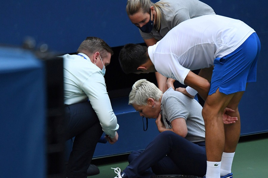 Novak Djokovic of Serbia and a US Open tournament official tend to a linesperson who was struck with a ball by the Serbian — USA Today Sports photo via Reuters