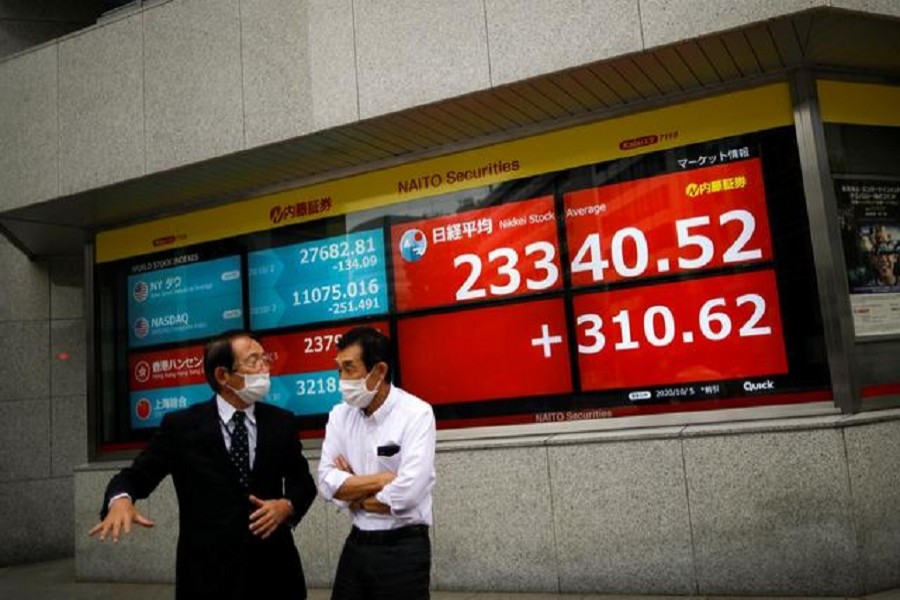 Men wearing protective face masks chat in front of a screen displaying Nikkei share average and world stock indexes outside a brokerage, amid the coronavirus disease (Covid-19) outbreak, in Tokyo, Japan, October 5, 2020 -- Reuters