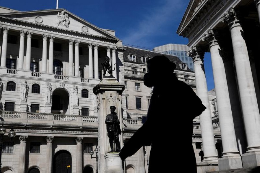 A person wearing a mask walks past the Bank of England in London, Britain on March 23, 2020 — Reuters/Files