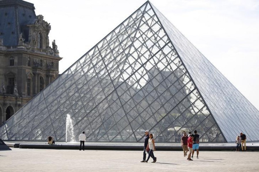 Tourists stand in front of the Louvre Pyramid designed by Chinese-born US Architect Ieoh Ming Pei in Paris, France — Reuters/Files