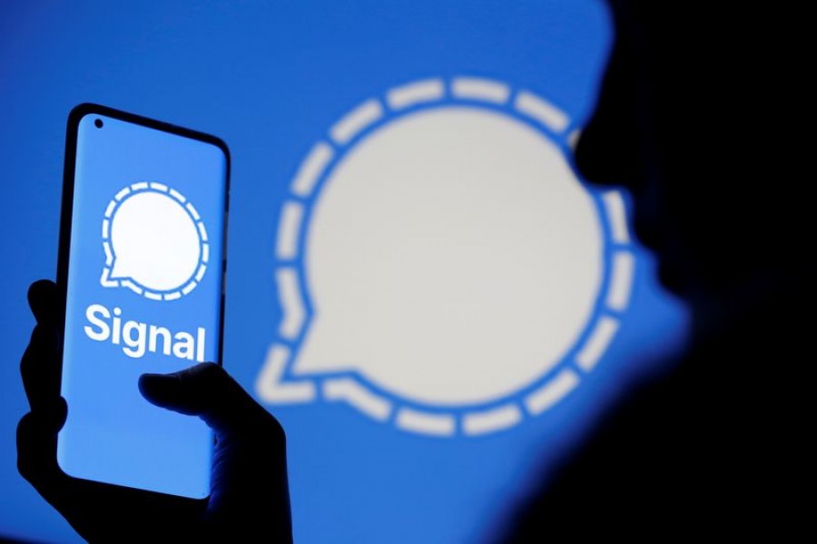 A woman holds a smartphone displaying the Signal messaging app logo, which is also seen near her, in this illustration taken January 13, 2021. REUTERS/Dado Ruvic