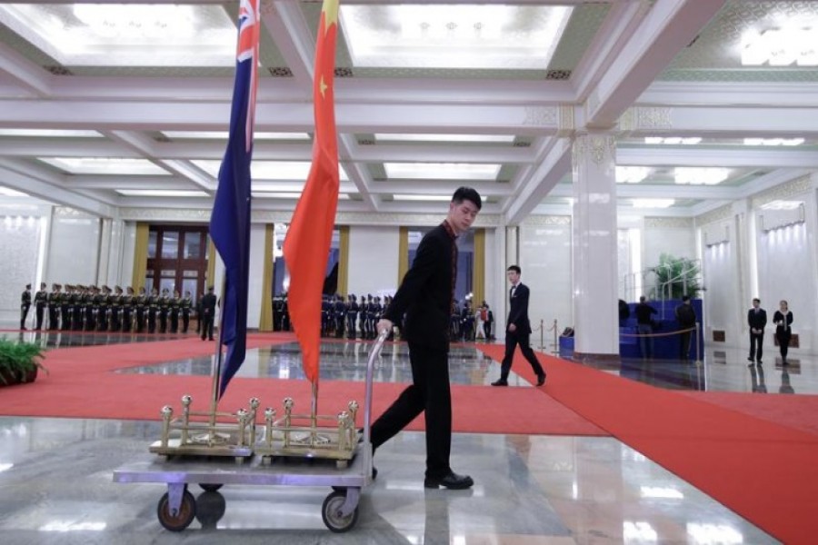 An attendant moves flags of New Zealand and China after a welcome ceremony for Prime Minister Jacinda Ardern at the Great Hall of the People in Beijing, China, April 1, 2019. REUTERS