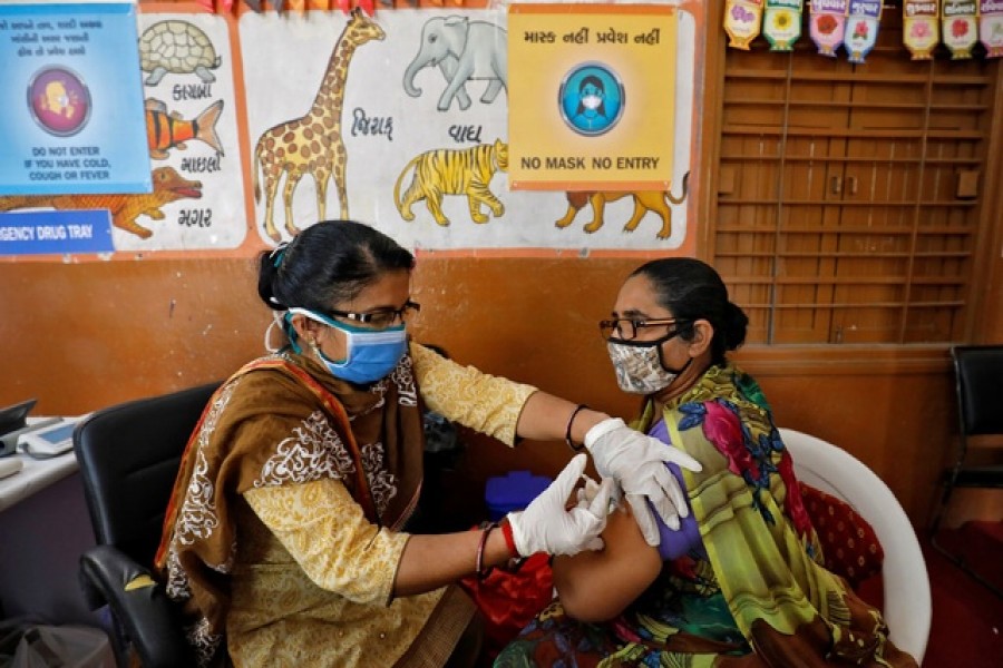 A health care worker receives a dose of COVISHIELD, a COVID-19 vaccine manufactured by Serum Institute of India, inside a classroom of school, which has been converted into a temporary vaccination centre, in Ahmedabad, India, February 9, 2021. Reuters