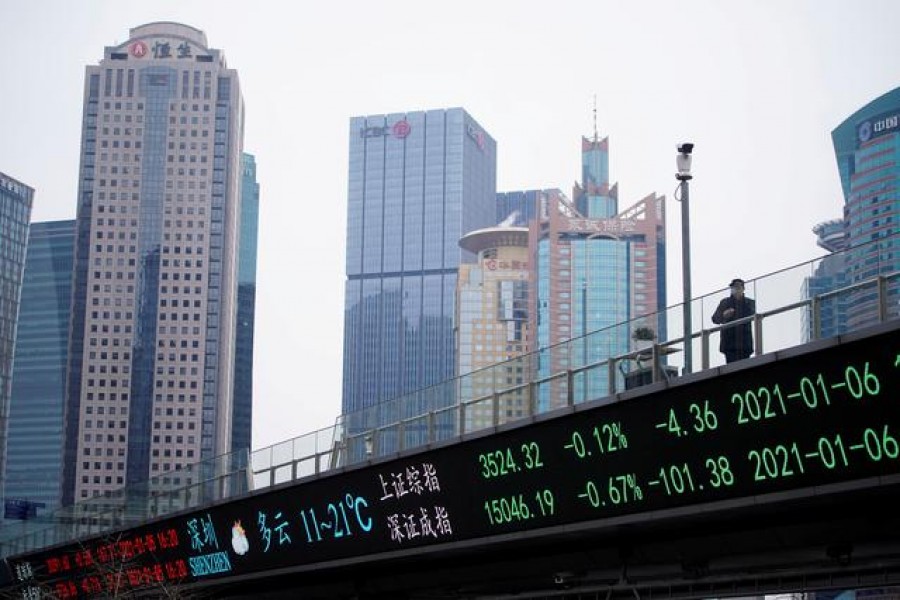 A man stands on an overpass with an electronic board showing Shanghai and Shenzhen stock indexes, at the Lujiazui financial district in Shanghai, China, January 6, 2021 — Reuters/Files