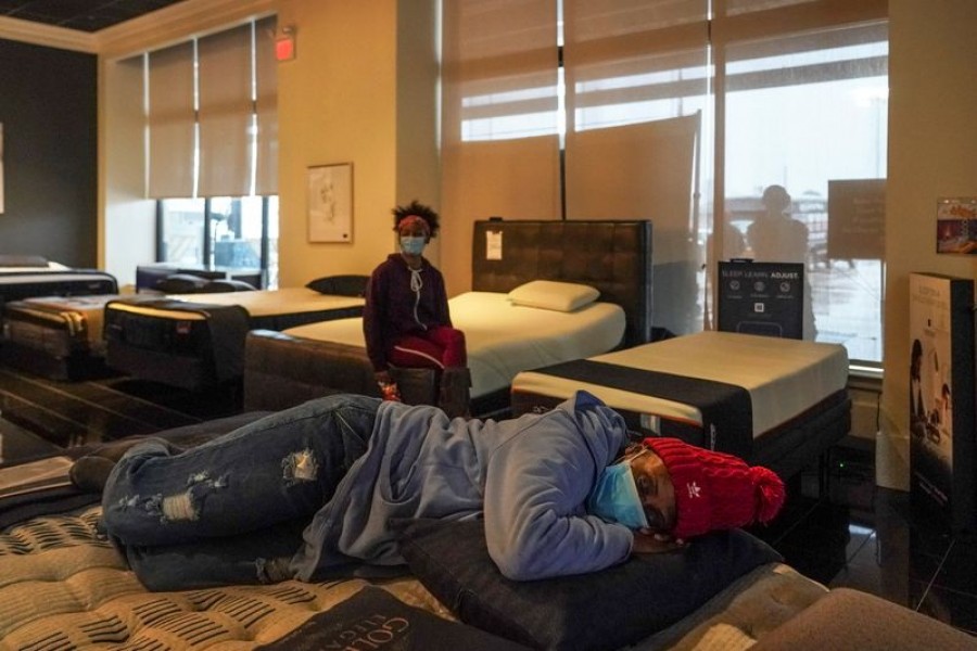Tiffany Woodley, front, rests on a bed while taking a shelter at Gallery Furniture store which opened its door and transformed into a warming station after winter weather caused electricity blackouts in Houston, Texas, US, February 17, 2021 — Reuters