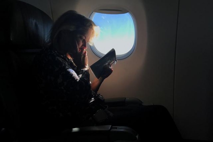 A woman reads while sitting in a business class seat on a flight from New York City to Washington D.C. U.S., December 7, 2017. REUTERS/Carlo Allegri/File Photo