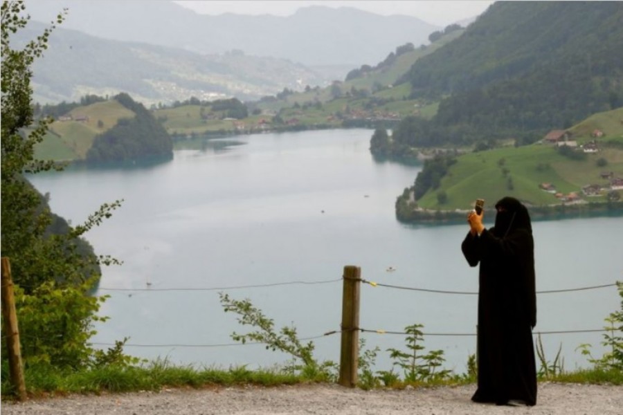 A woman wearing a niqab takes a picture from a lookout above lake Lungenersee at the Bruenigpass mountain pass road, Switzerland August 3, 2017. On March 7 Switzerland's voters will decide about a nationwide veil ban. REUTERS