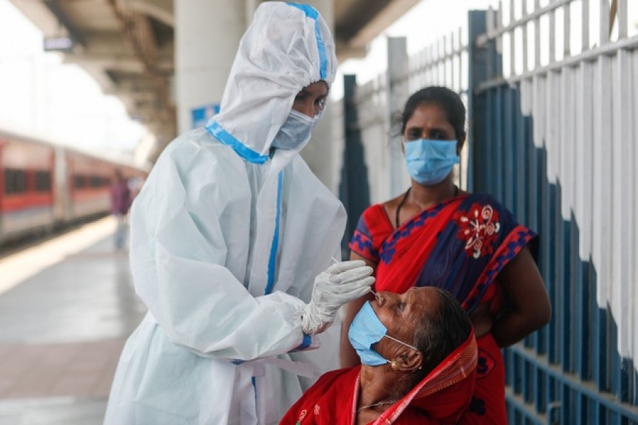 A healthcare worker in personal protective equipment (PPE) collects a swab sample from a woman, amidst the spread of the coronavirus disease (Covid-19), at a railway station in Mumbai, India, April 16, 2021 — Reuters