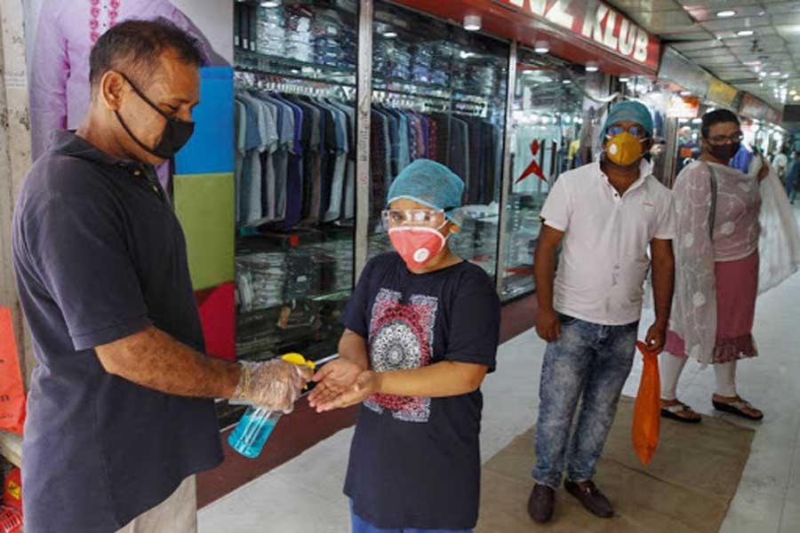 A staff gives a child hand sanitizer at a reopened market in Dhaka last year       —Xinhua photo