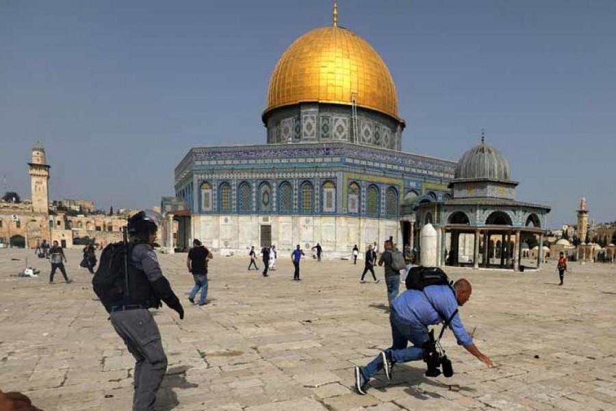 A camera operator falls as an Israeli police officer runs after him during clashes with Palestinians at the compound that houses Al-Aqsa Mosque, known to Muslims as Noble Sanctuary and to Jews as Temple Mount, in Jerusalem's Old City, May 10, 2021- Reuters