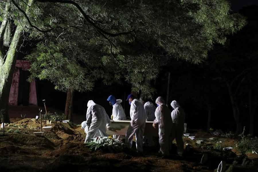 Gravediggers wearing protective suits carrying a coffin as spotlights illuminate the graves during a night burial at Vila Formosa cemetery, amid the coronavirus disease (COVID-19) pandemic, in Sao Paulo of Brazil on April 28 this year -Reuters file photo