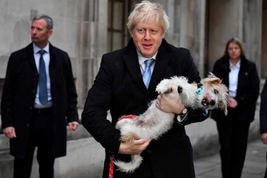 Britain's Prime Minister Boris Johnson holds his dog Dilyn as he leaves a polling station, at the Methodist Central Hall, after voting in the general election in London, Britain, December 12, 2019. REUTERS/Dylan Martinez