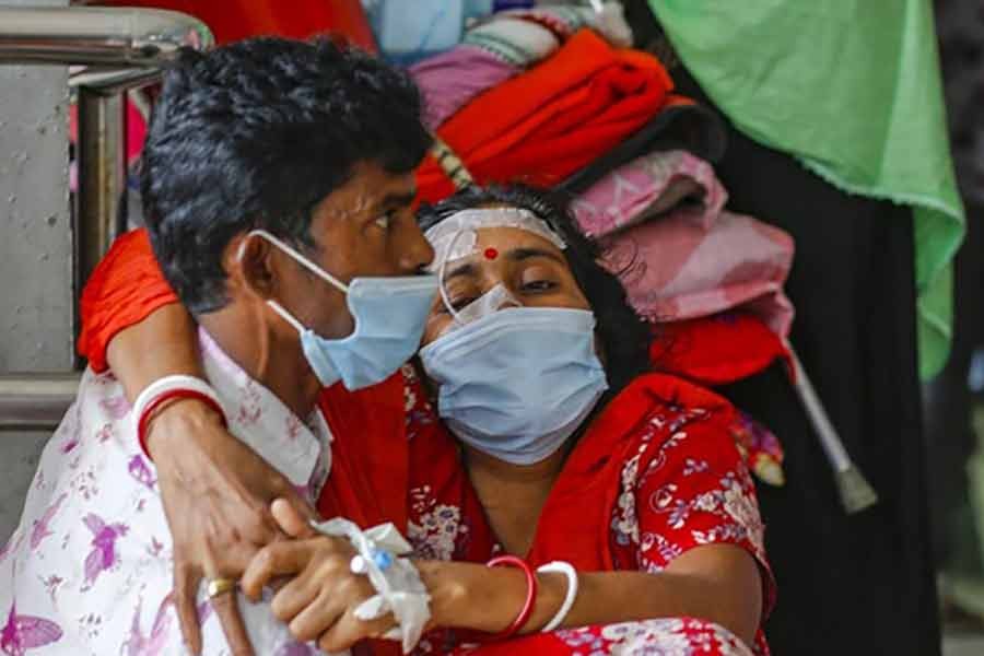 Husband carrying suspected coronavirus patient Shipra, who gave a single name and also has typhoid, into Dhaka Medical College Hospital as they arrive from Bogura recently  -bdnews24.com file photo
