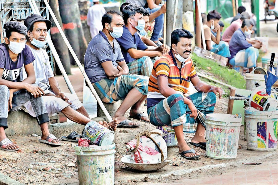 A group of day labourers waiting for employers to come and hire them for work in the Naya Bazar area of the city on Friday. This low-income section of society is facing hardship due to a lack of work opportunities during the ongoing lockdown enforced to stem the spread of coronavirus — FE photo by Shafiqul Alam