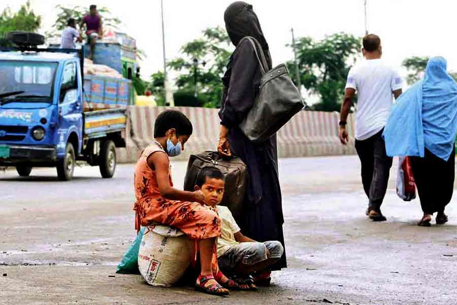 A woman, along with two children, is waiting for a vehicle at Gabtoli in Dhaka on Monday. They somehow managed to reach the outskirt of Dhaka during suspension of long-haul transportation services amid the Covid-induced lockdown, but found it difficult to get a vehicle to ferry them inside the city —FE photo by KAZ Sumon