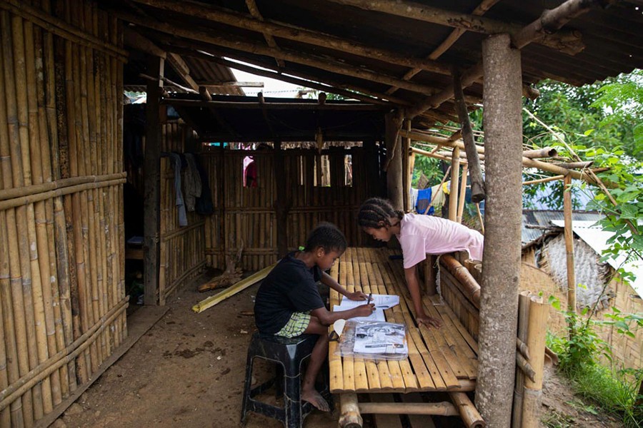 Seventh grade student Ryza Delos Santos, 10, works on her modules at home as her cousin observes, after a session at the makeshift rickshaw distance learning centre for the Aeta community in Porac, Pampanga, Philippines on October 12, 2020 — Reuters