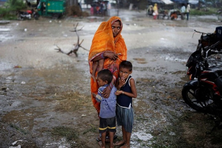 A woman stands with her children as she waits to receive a dose of COVAXIN COVID-19 vaccine manufactured by Bharat Biotech, during a vaccination drive organised by SEEDS, an NGO which normally specialise in providing relief after floods and other natural disasters, at an under-construction flyover in New Delhi, India, Aug 31, 2021. REUTERS/Adnan Abidi