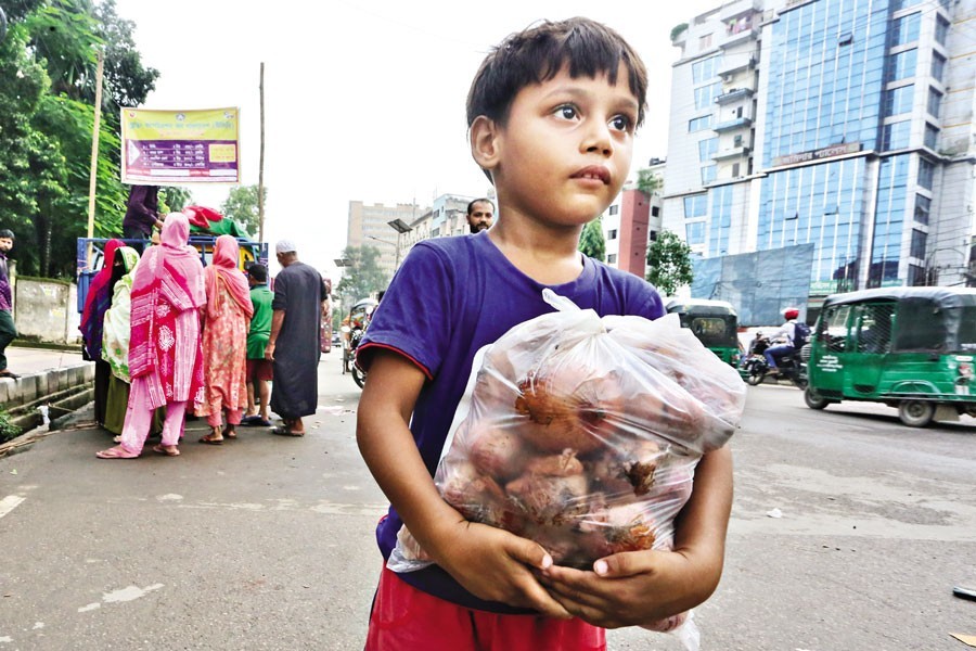 This happy kid returns home with onions bought at a subsidised price from a TCB sales point in the Fakirapool area of the city on Thursday. The rising prices of daily commodities have simply made the life of low-income people difficult — FE photo by KAZ Sumon