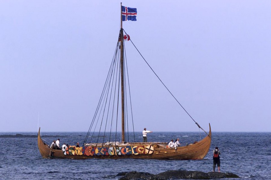 A tourist (R) photographs the Viking replica ship the Islendingur as it arrives in the fishing village of L'Anse aux Meadows in Newfoundland on July 28, 2000 — Reuters/Files