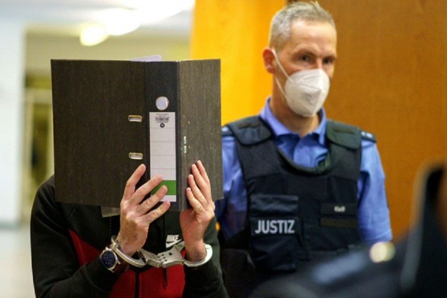 Iraqi defendant Taha Al-J covers his face as he arrives before his verdict in a courtroom in Frankfurt, Germany, November 30, 2021. The 31-year-old Iraqi IS supporter is accused of using a 5-year-old Yazidi girl as his slave before he left her to die in the summer heat. Frank Rumpenhorst/Pool via REUTERS